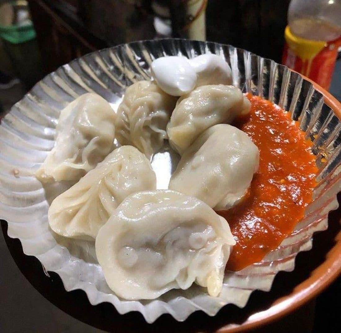 A plate of steamed momos with fiery red chutney in Dehradun