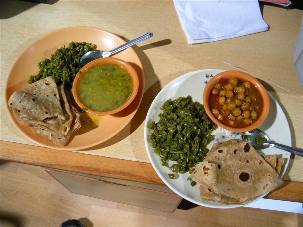 A vegetarian North Indian meal of chole, saag and roti on steel plates