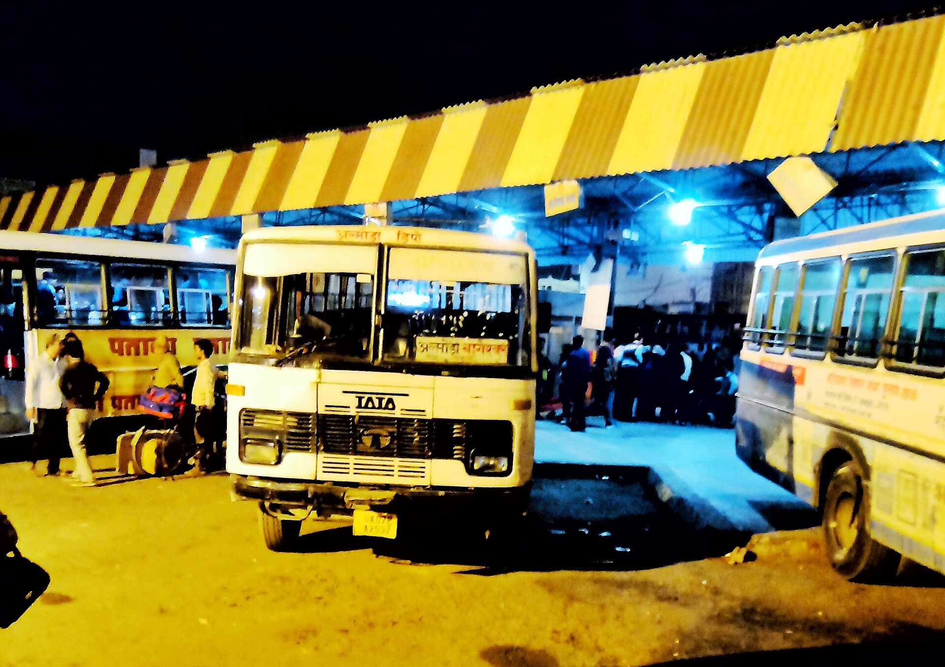 Uttarakhand Roadways buses loading passengers at a Dehradun bus stand at night