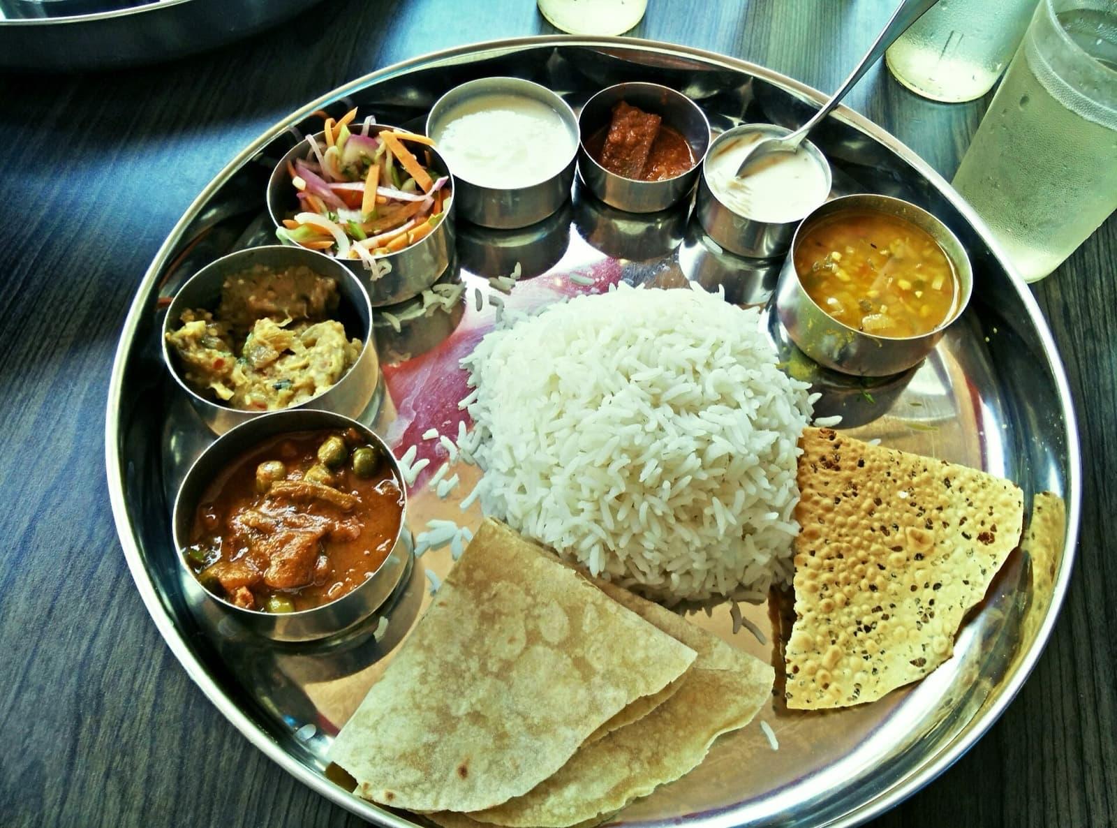A classic North Indian thali with rice, dal, curry, roti and papad