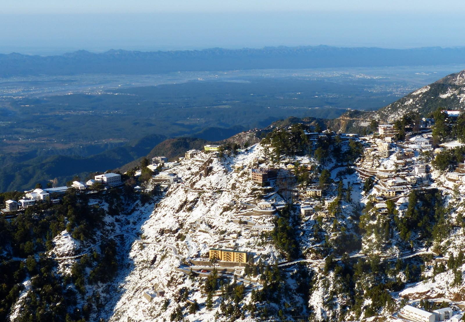 Snow on the Mussoorie hillside with the Doon valley and Dehradun spread out below