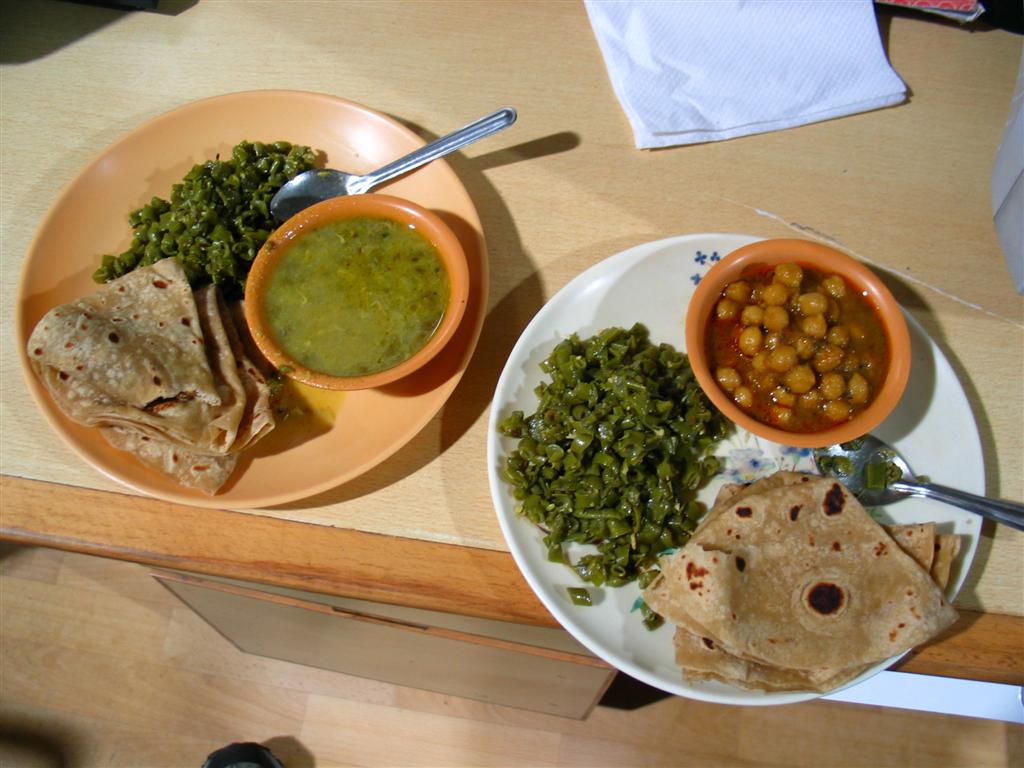 A vegetarian North Indian meal of chole, saag and roti on steel plates